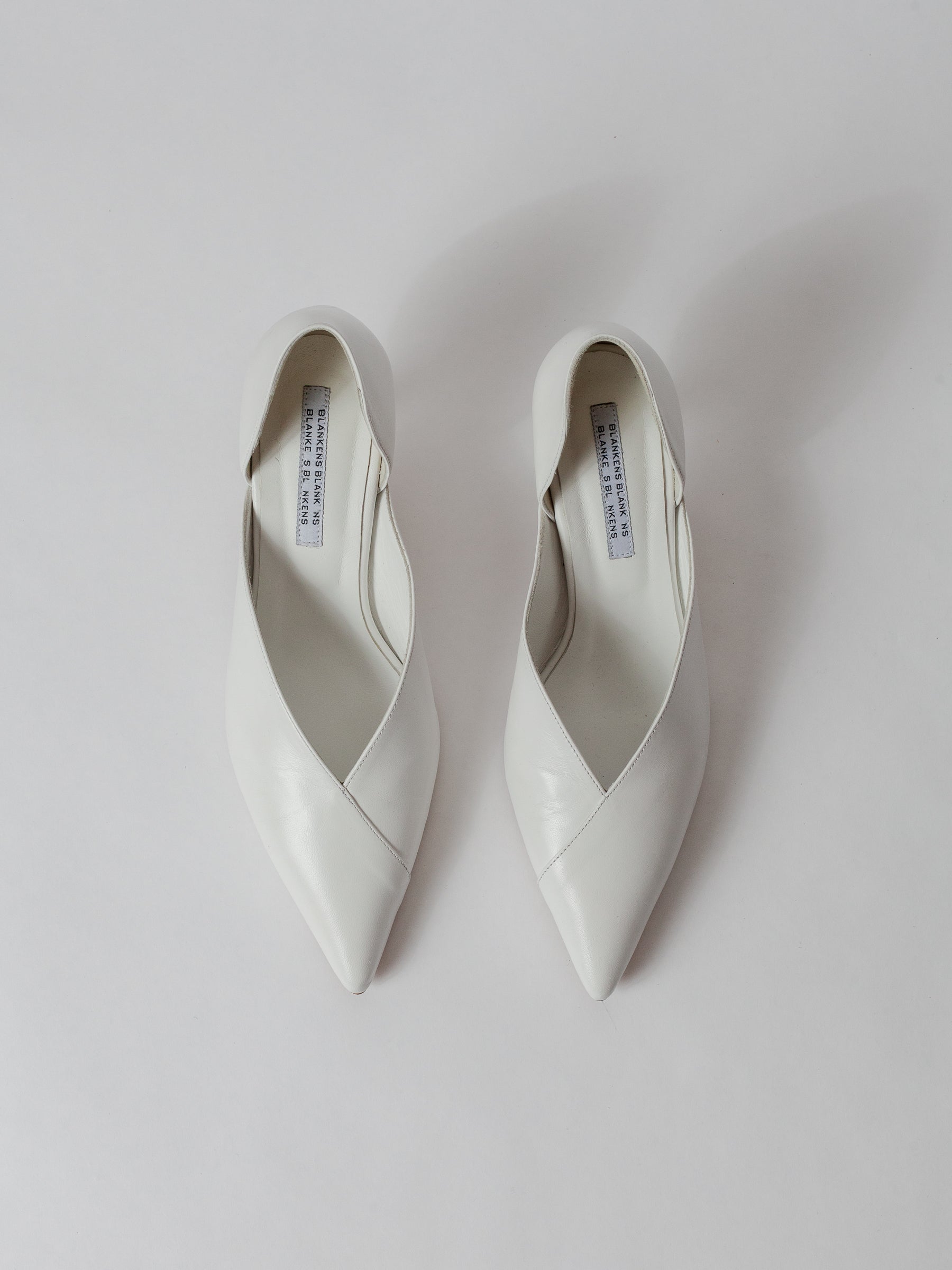Blankens The Radford white Pair of white pointed-toe shoes on a light gray background