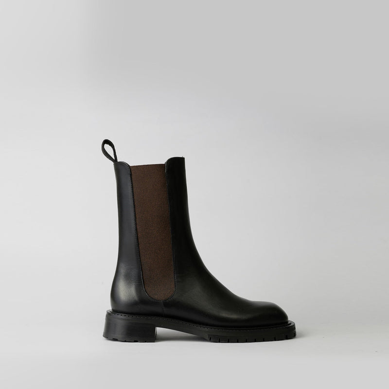 Black Chelsea boot with brown side panel on a light gray background
