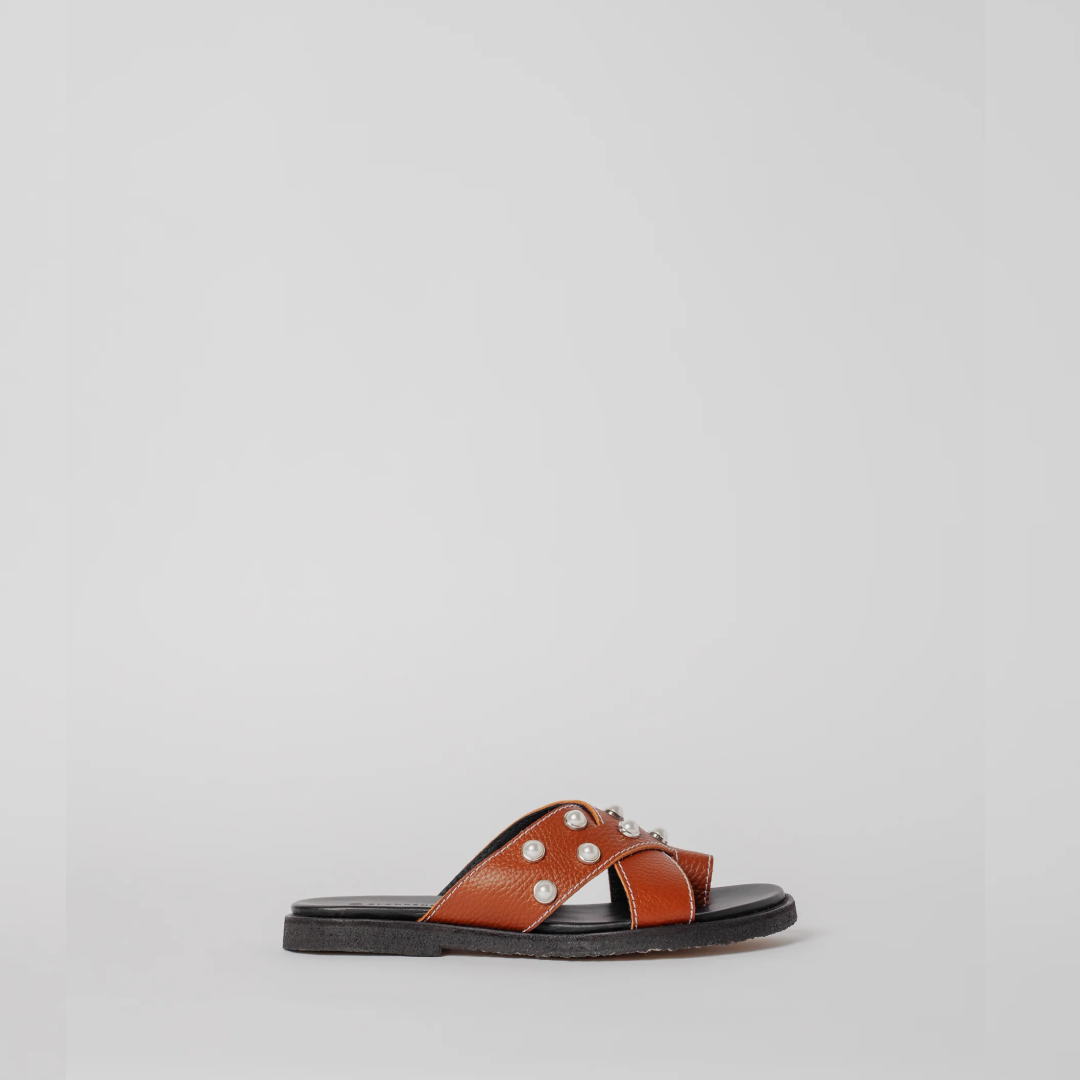 Brown sandal with decorative elements on a light gray background