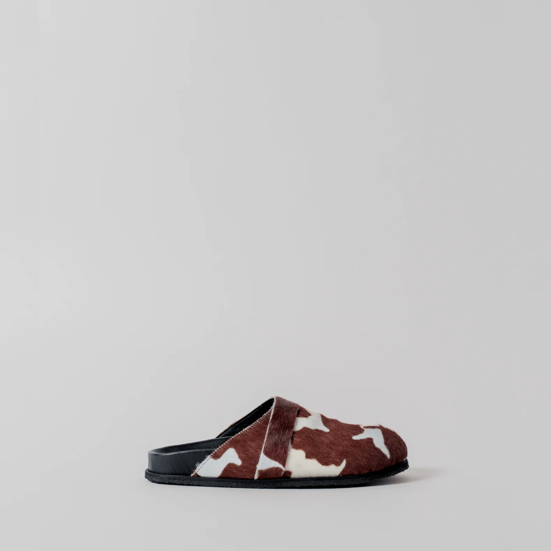 Brown and white cow print slipper on a light gray background