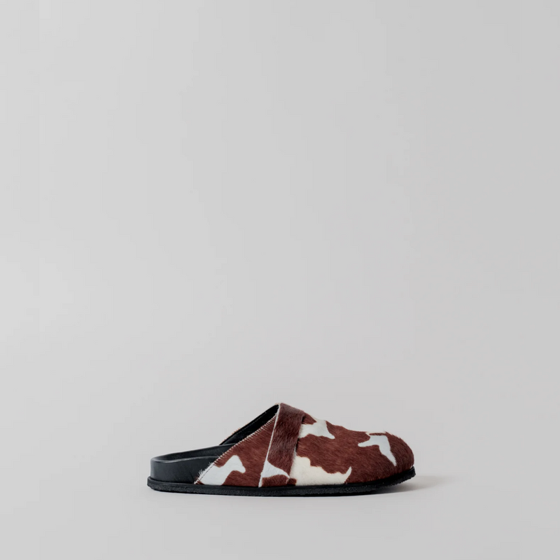 Brown and white cow print slipper on a light gray background